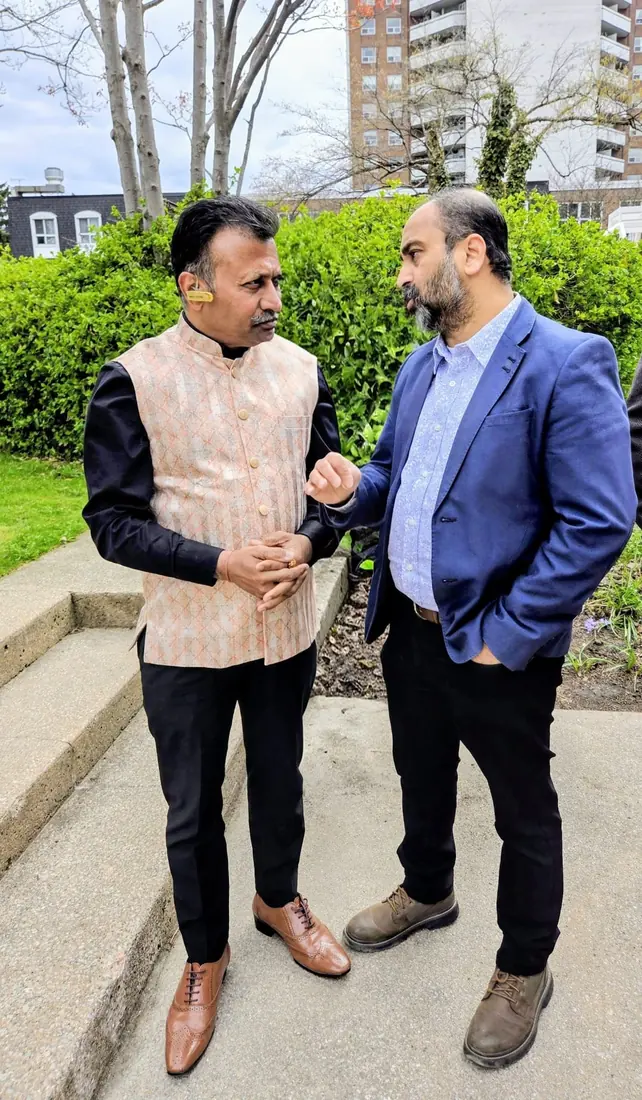 Husain in conversation with a community leader outdoors
