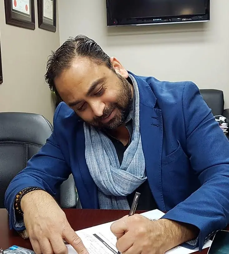 Husain signing documents in an office