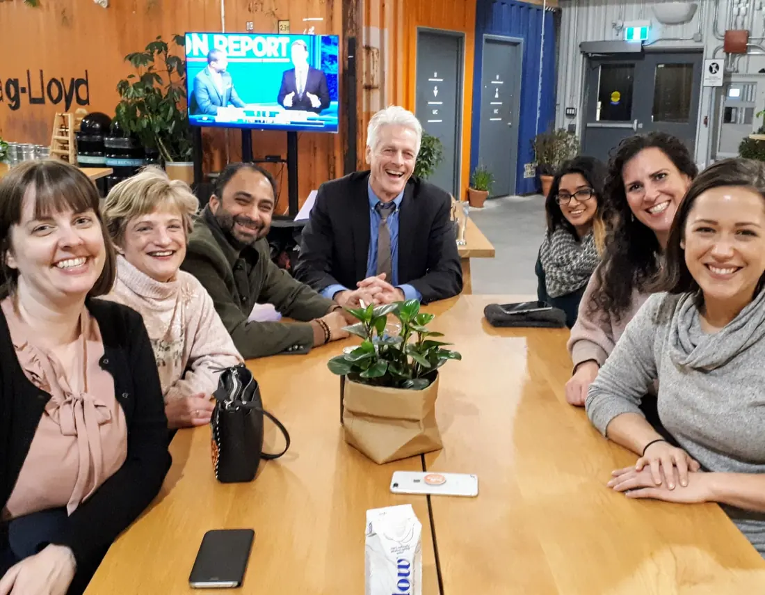 Husain at a team meeting around a table